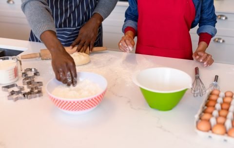 midsection-african-american-couple-wearing-aprons-baking-together-min